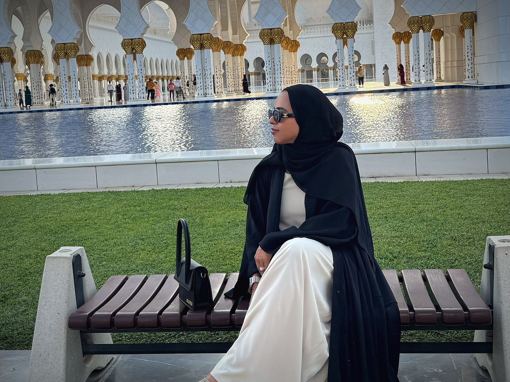 Sanaa seated beside a mosque courtyard and reflection pool